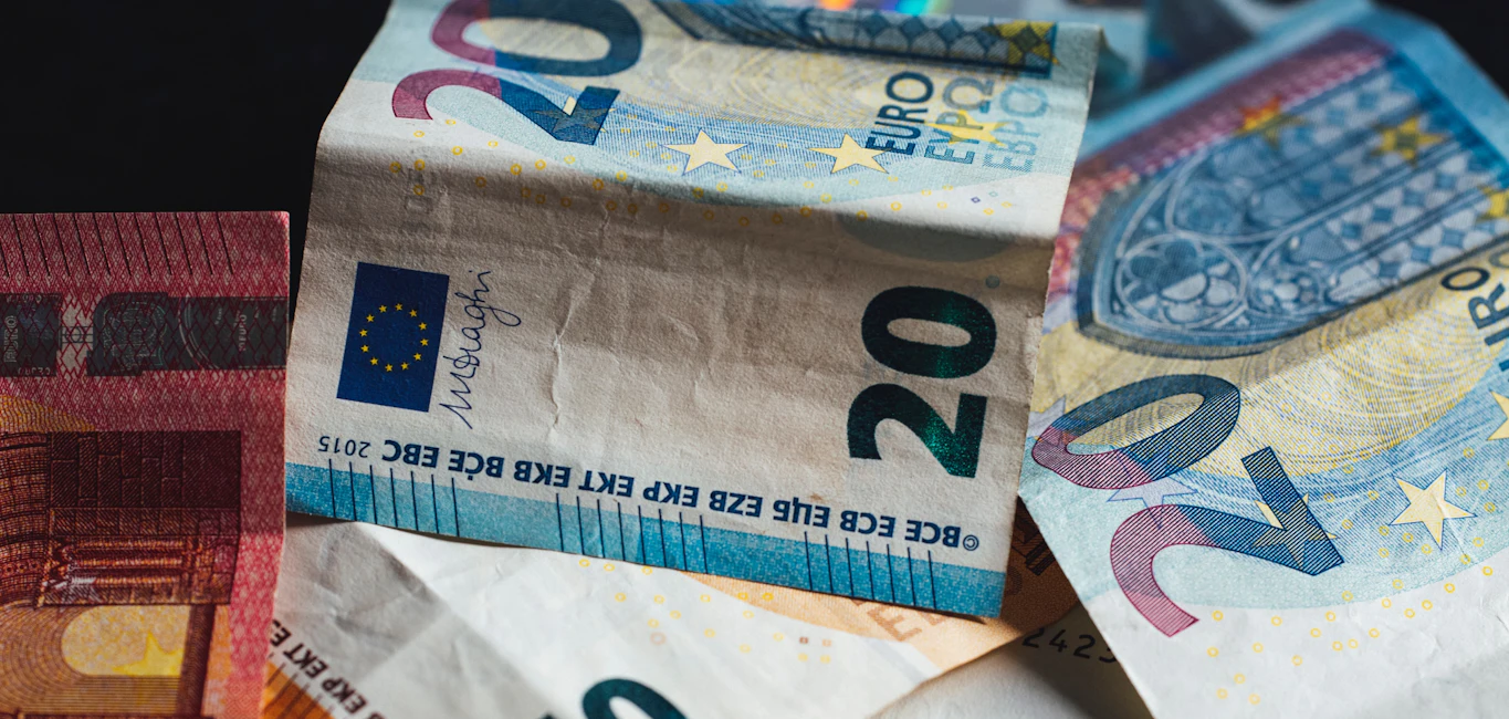 Verkreukelde eurobiljetten van twintig euro door elkaar op een donkere ondergrond